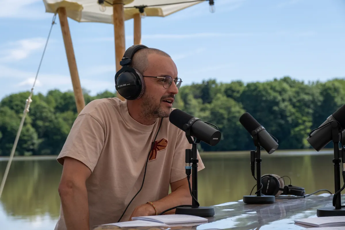 Jeremy Debreu au micro de Festoche!, casque sur les oreilles, au bord du lac du Malsaucy